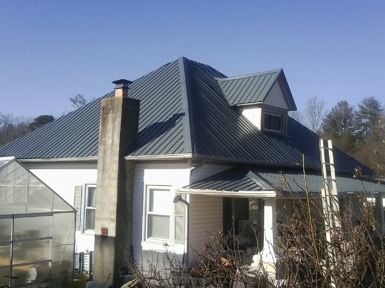 Dark blue standing seam metal roof on a white farmhouse with dormer — Slate & Tile Roof Repair by Roofing Brothers in Napoleon