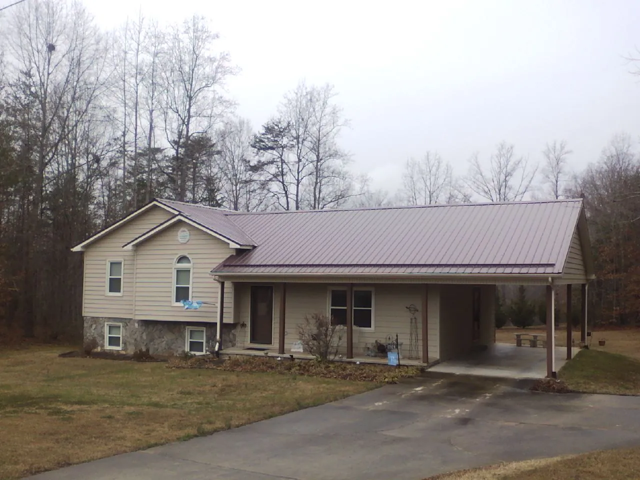 Burgundy metal roof on a tan split level home with an attached carport in Napoleon
