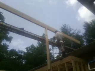 Carpenter setting a ridge beam over a new addition frame — Ice Dam Removal by Roofing Brothers in Napoleon